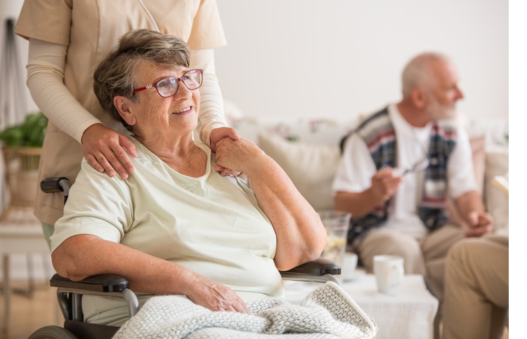 Happy senior lady sitting at wheelchair in nursing home for elderly