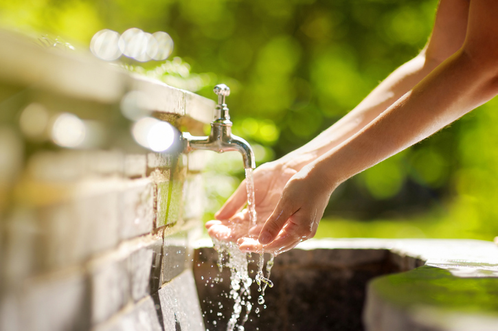 closeup photo of woman washing hands in a city fountain