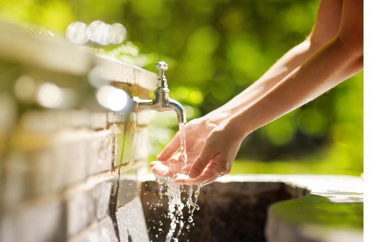 closeup photo of woman washing hands in a city fountain