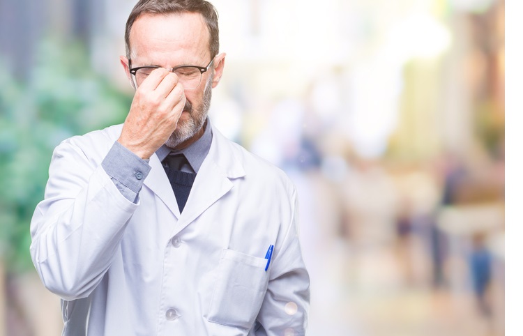 Middle age senior hoary professional man wearing white coat over isolated background tired rubbing nose and eyes feeling fatigue and headache. Stress and frustration concept