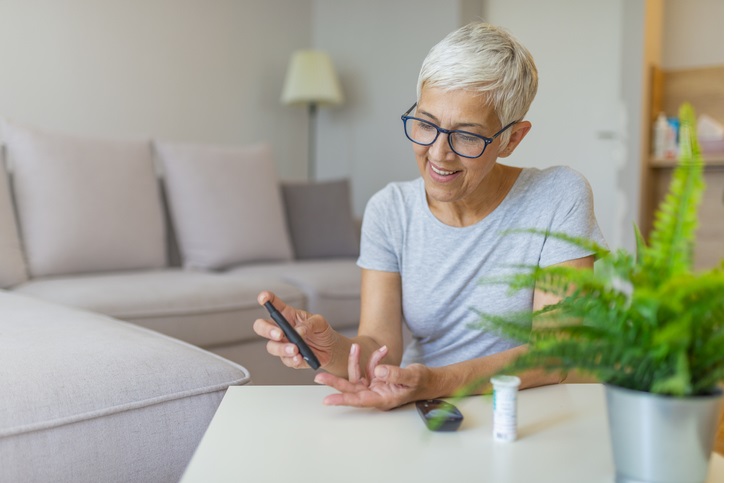 Woman checking blood sugar level by glucometer and test stripe at home