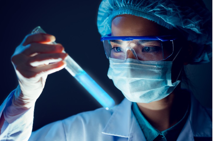 Medical researcher holding test tube with blue fluorescent liquid