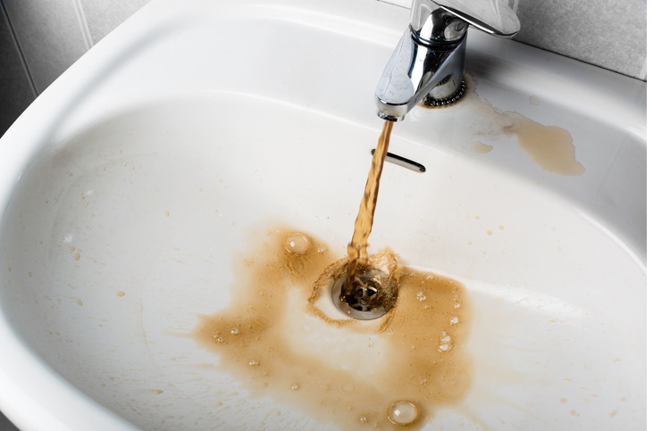 Dirty brown water running into a white sink