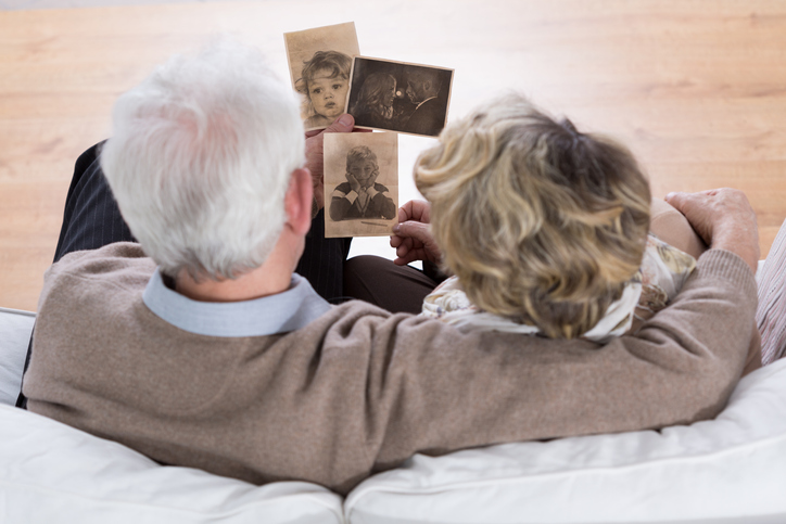 Senior marriage sitting on the sofa and looking at old photos