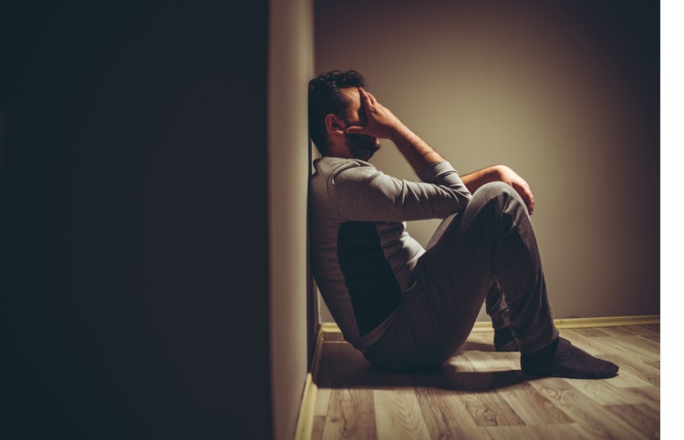 Young depressed man sitting on floor