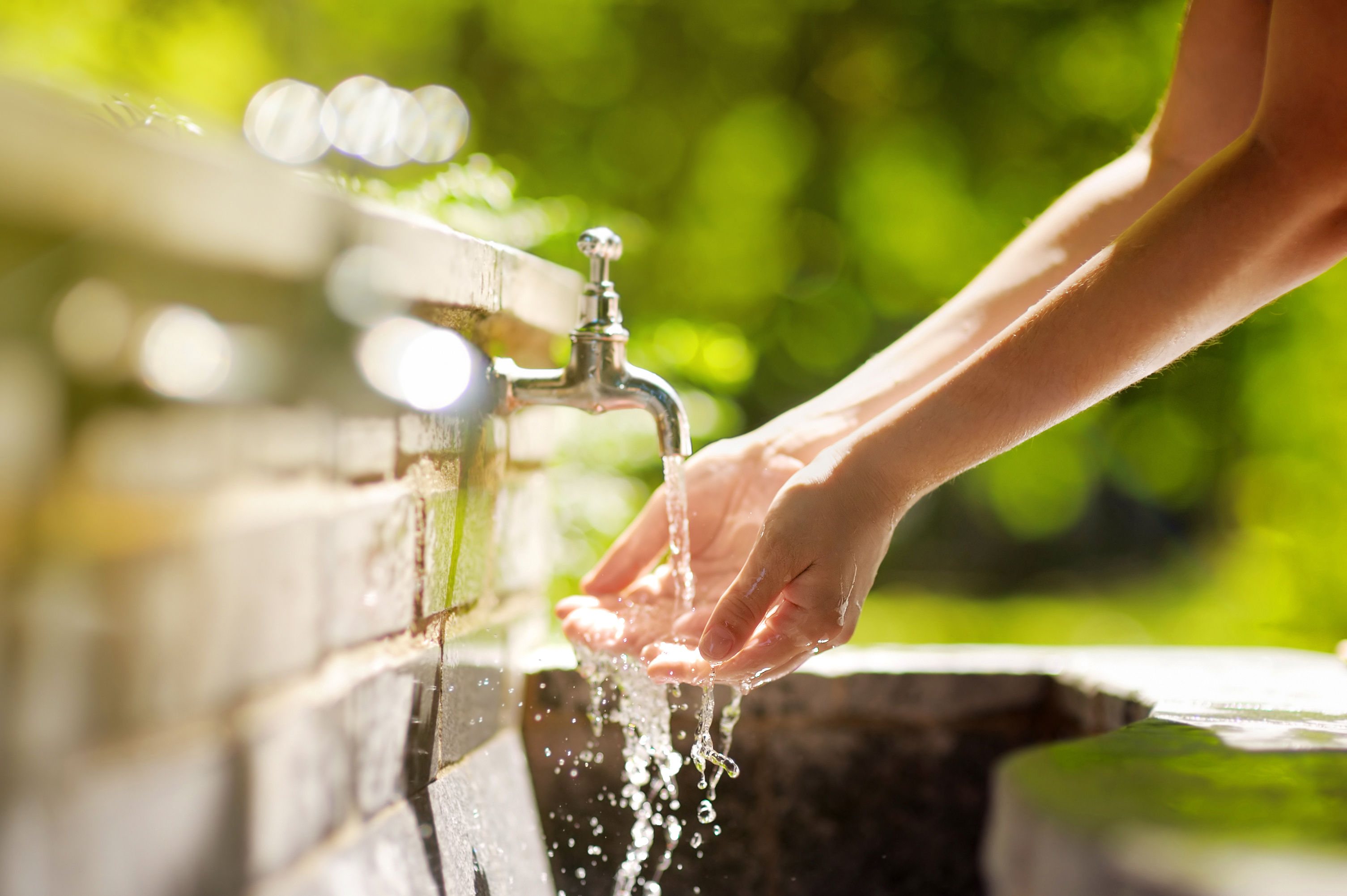 loseup photo of woman washing hands in a city fountain