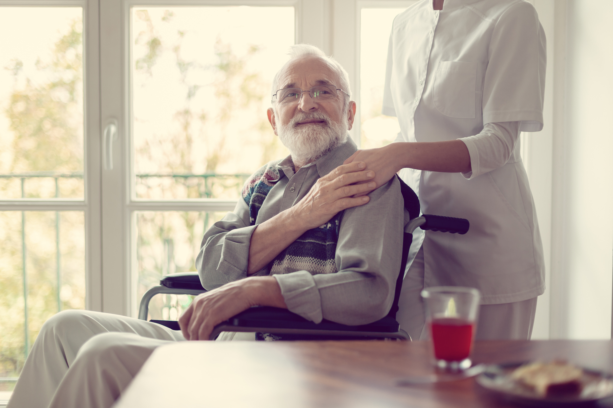 Senior patient in nursing home with helpful nurse in white uniform