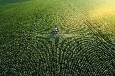 Traktor beim Ausbringen von Pestiziden auf dem Feld