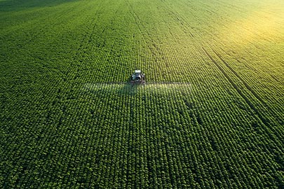 Traktor beim Ausbringen von Pestiziden auf dem Feld