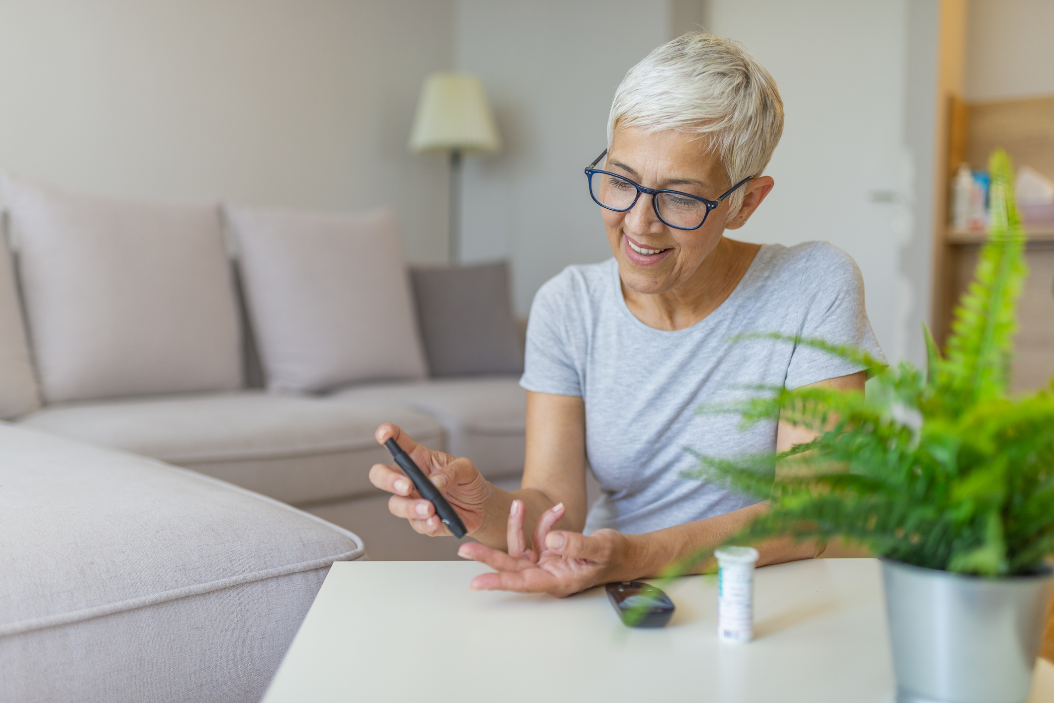 Woman checking blood sugar level by glucometer and test stripe at home