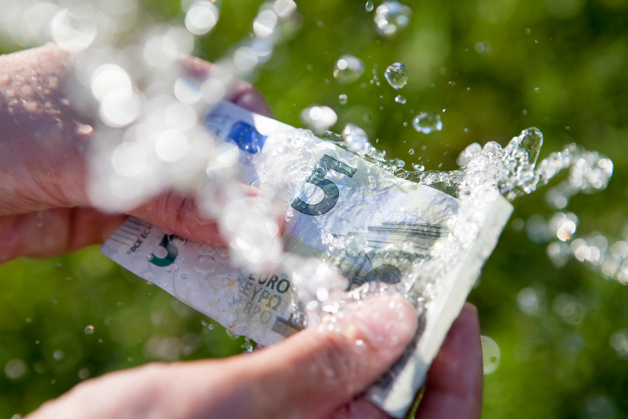 Two hands washing 5 euro banknote clean