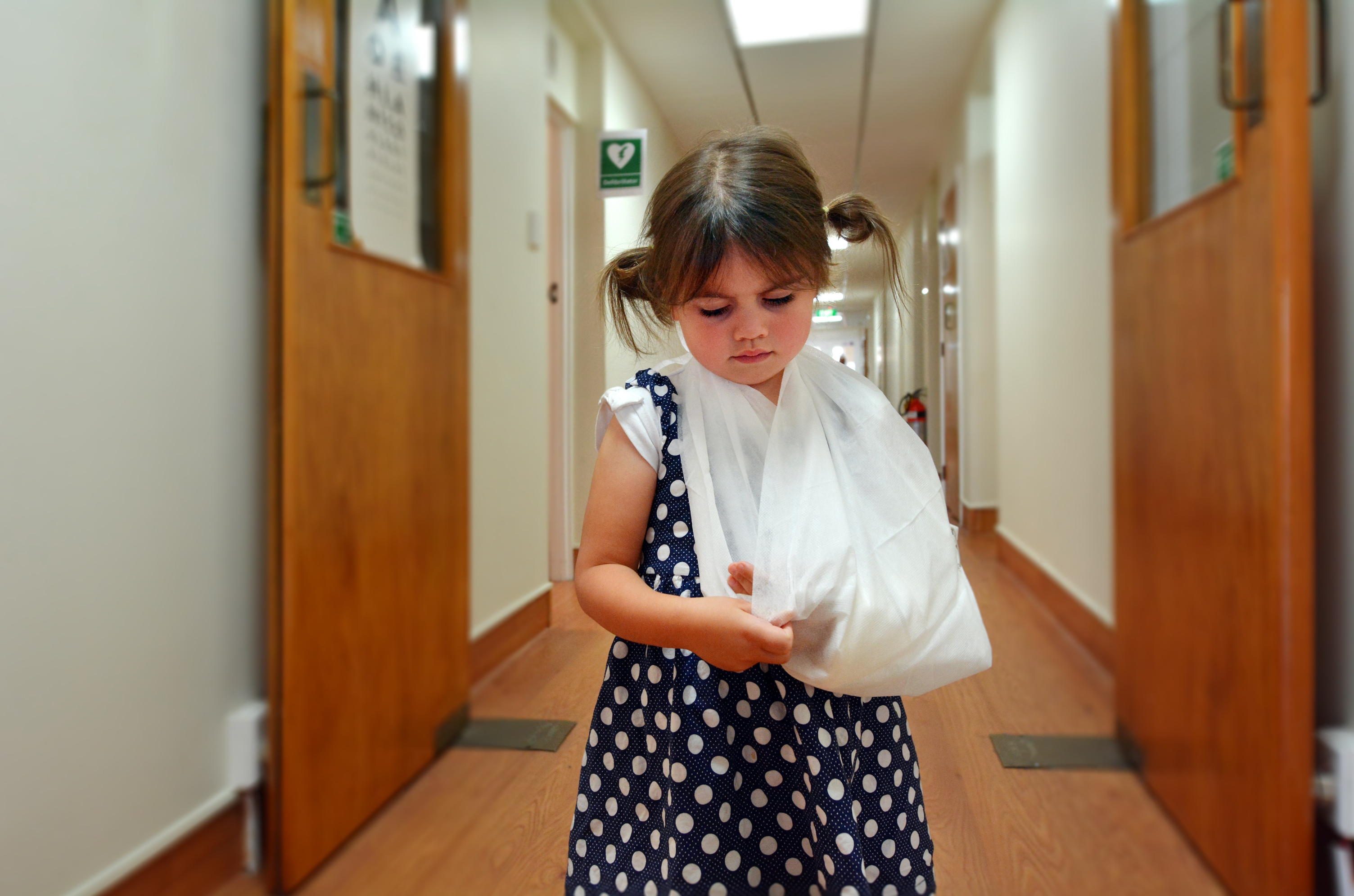 Sad little girl with a broken arm in hospital corridor.